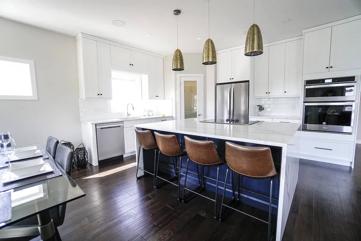 Photo of white kitchen cabinets, and white marble island countertop.